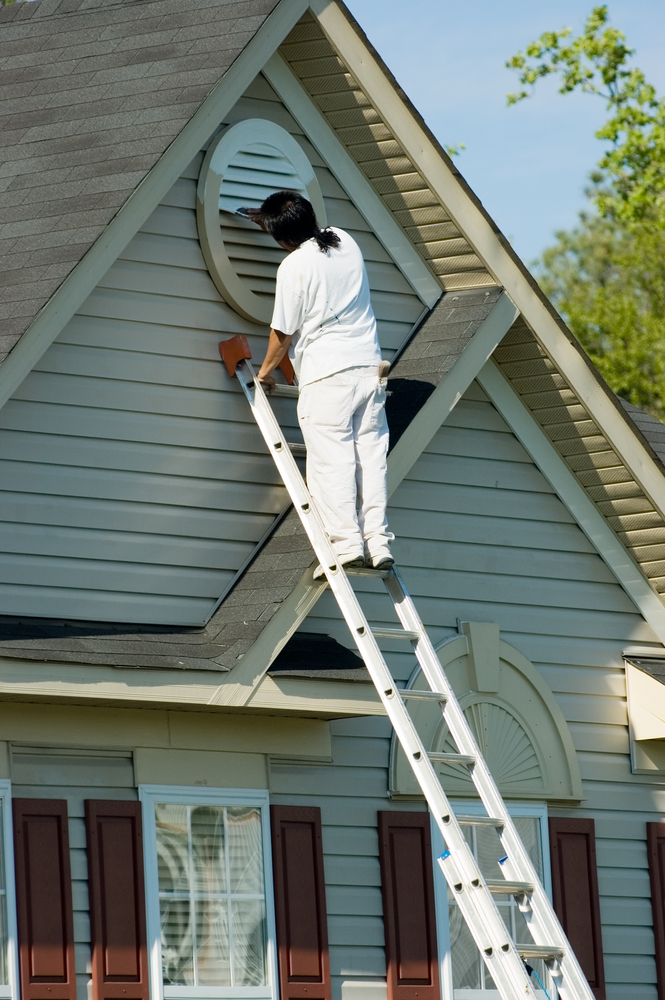 painter on ladder painting house