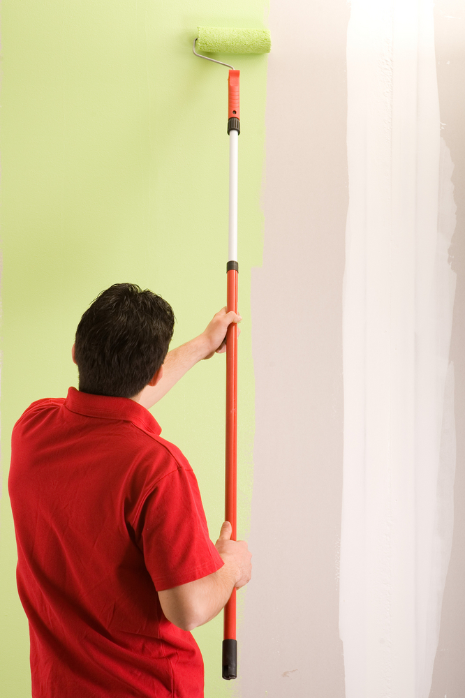 man in red shirt painting wall green